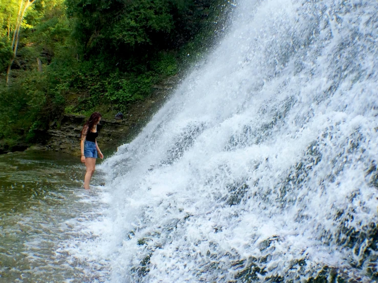 a woman stands in front of a waterfall