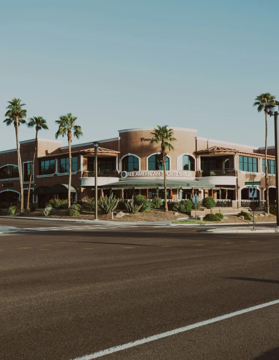 the road runs between a building and several palm trees