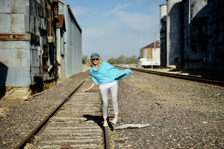 a woman riding a skateboard down the middle of a set of tracks