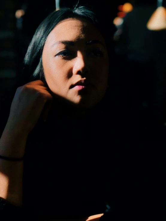 a young woman looks away while holding her hand near her head