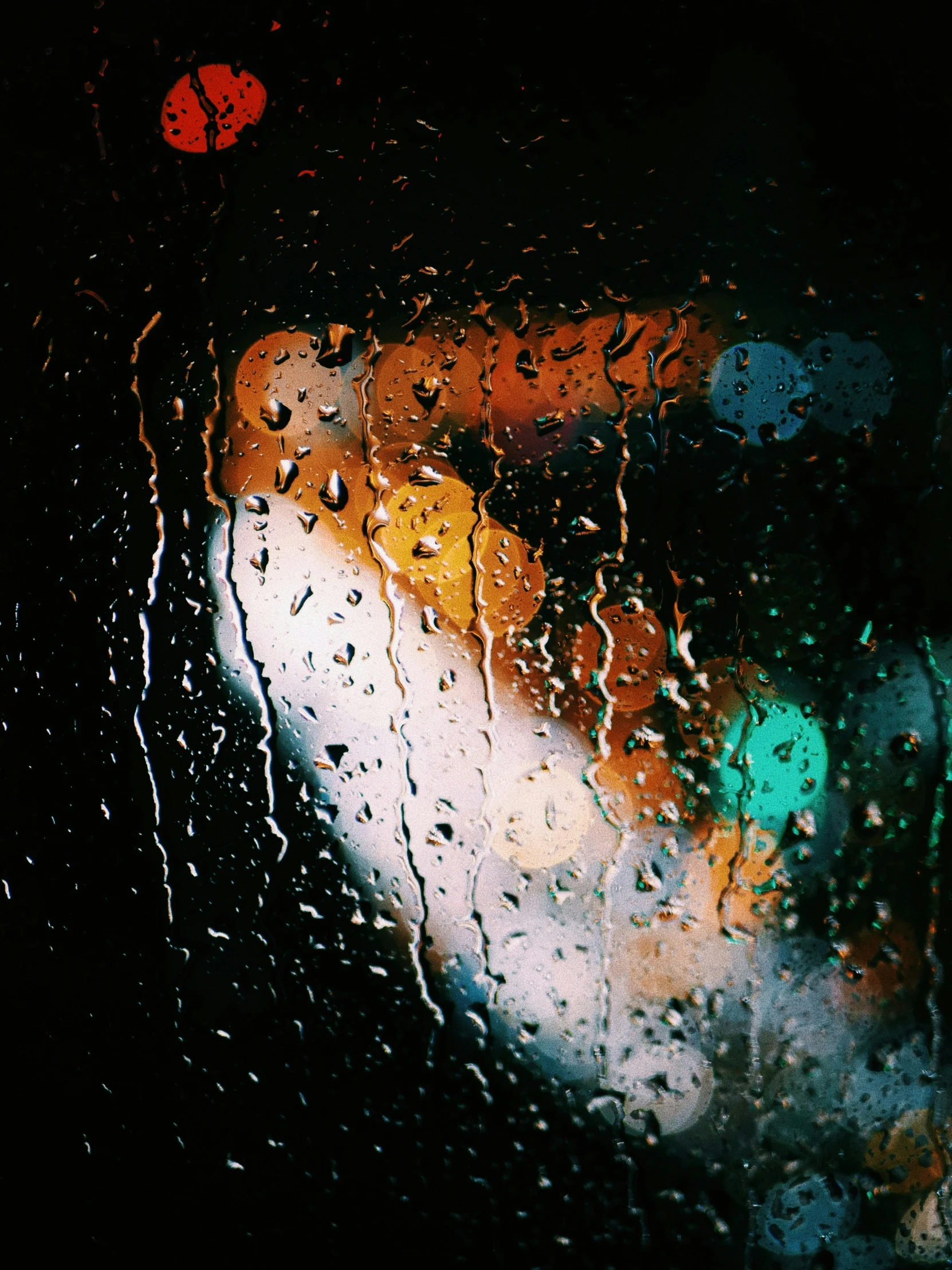 a view through a rainy windshield of traffic signals