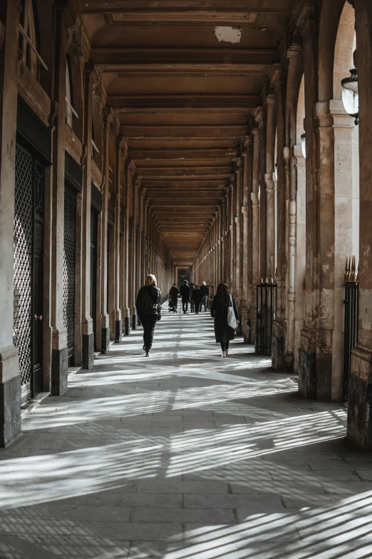 the long walkway is lined with columns and people