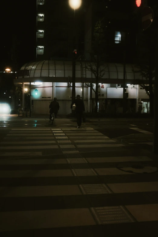 a person rides a bicycle at night on a street