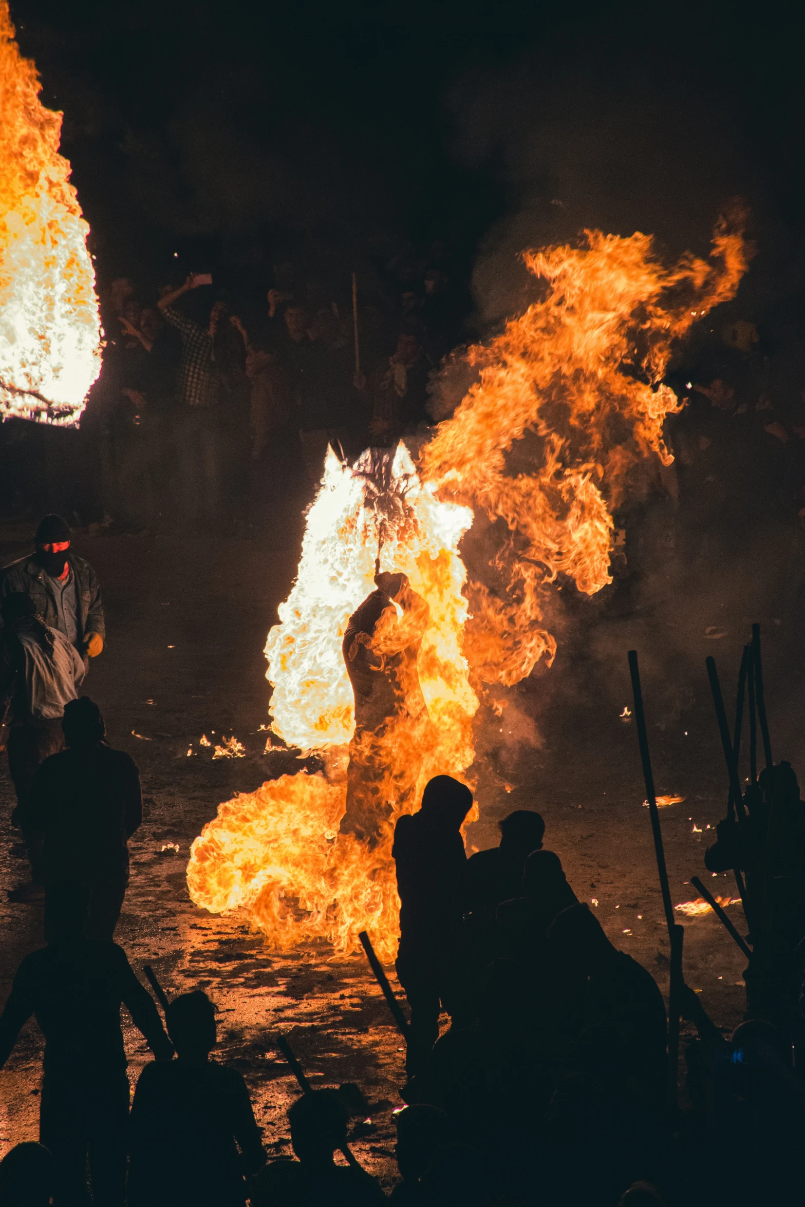 people stand near bright orange fire as they gather around