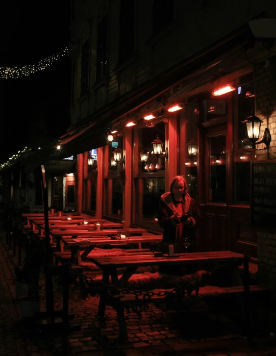 a woman stands at a wooden table with bright lights on it