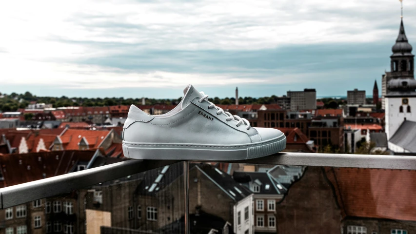 a white tennis shoe rests atop a railing overlooking the city