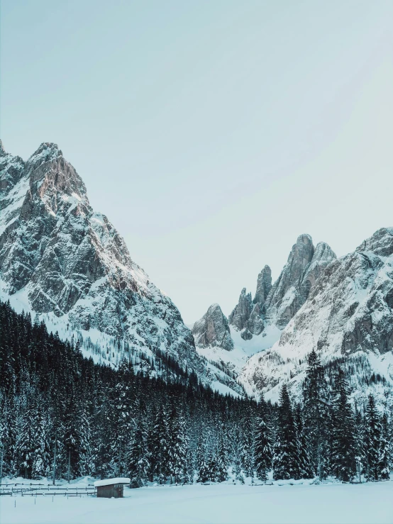 snowy mountains are behind a building and a lake