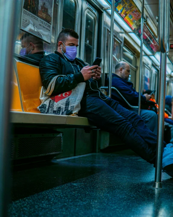 people wearing masks are sitting on a subway