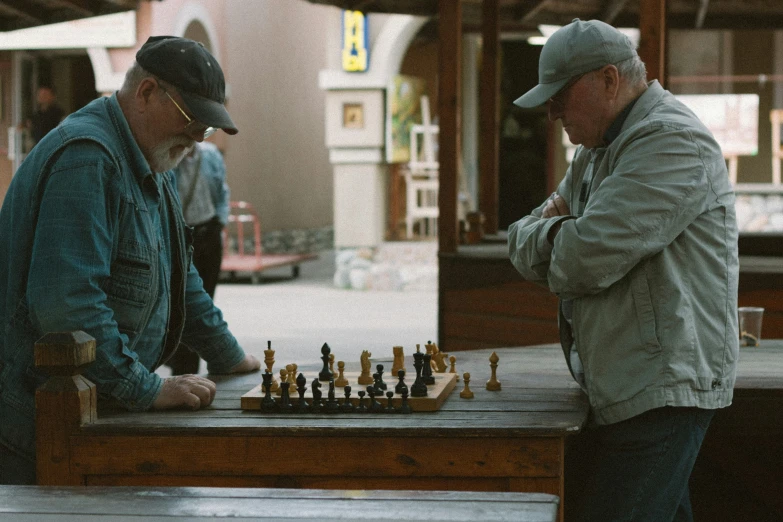 a couple of men standing next to each other near a chess board