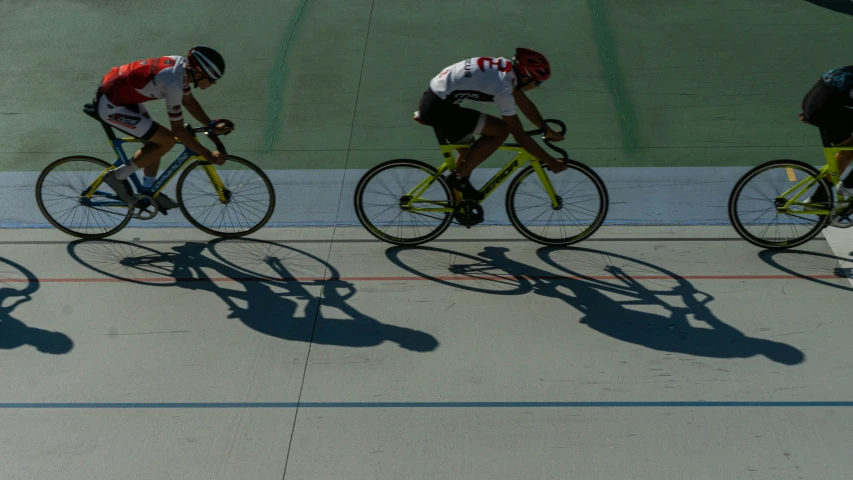 three different athletes racing bikes down a track