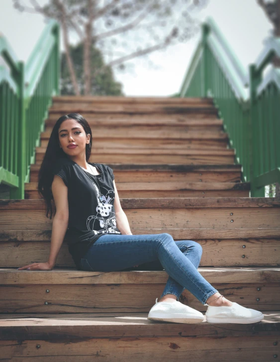 woman sitting down on a wooden staircase looking at the camera