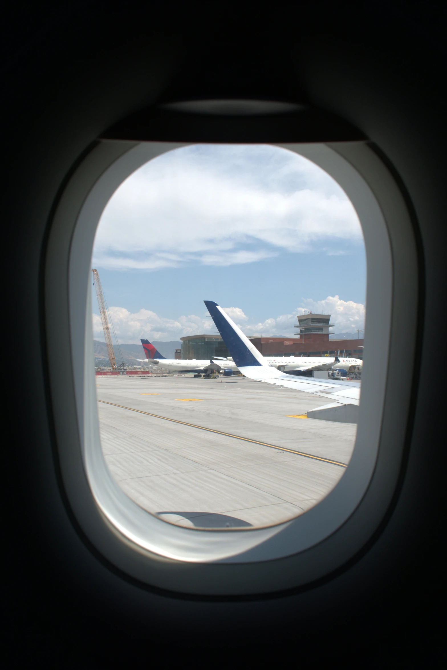 an airplane window looking out at planes on a runway