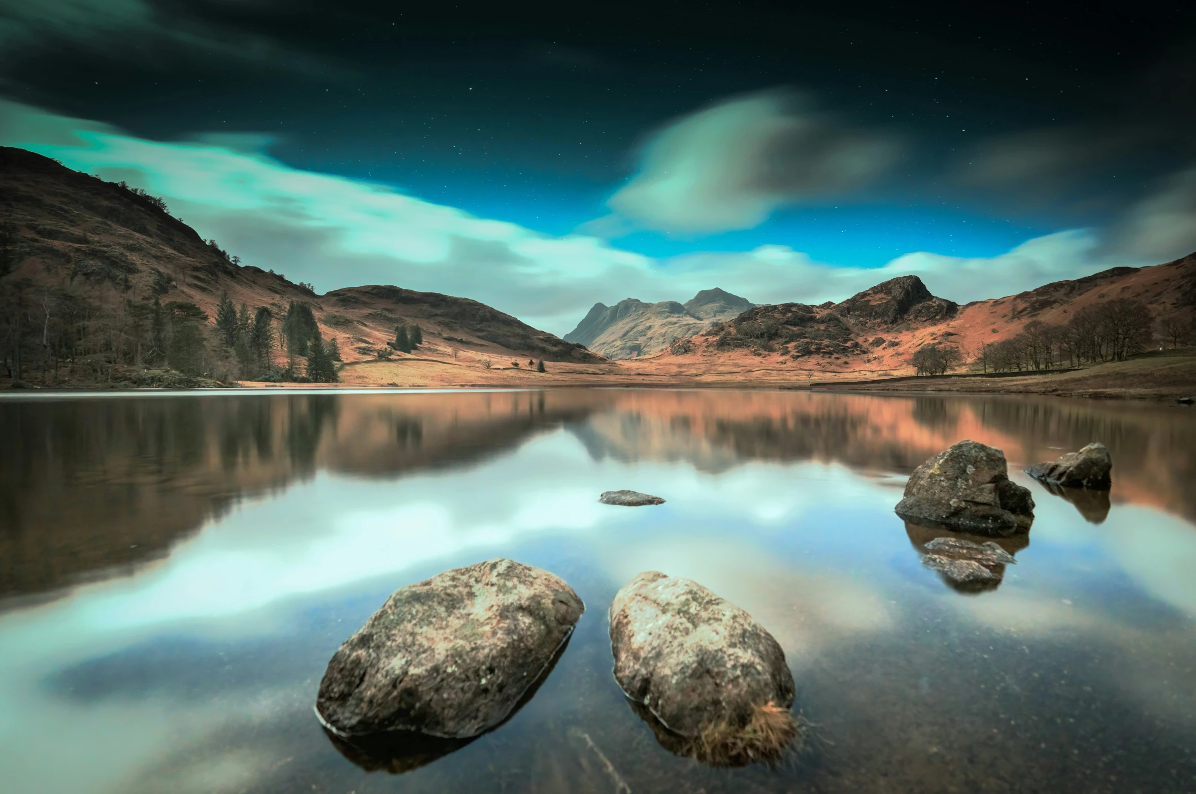 two large boulders sitting on a crystal lake under an aurora bore sky