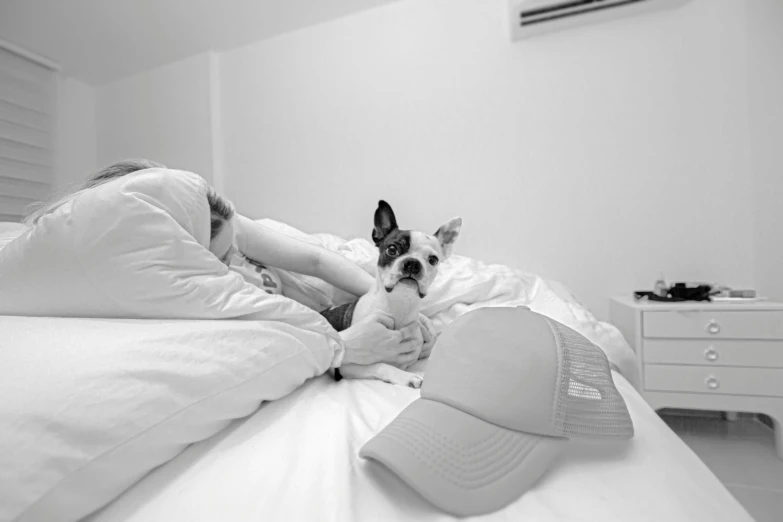 a dog laying in bed with a person and a hat on