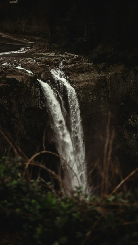 an open waterfall surrounded by greenery and water