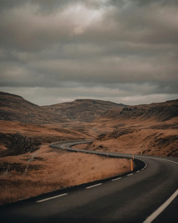 a long and empty road with brown grass in the foreground