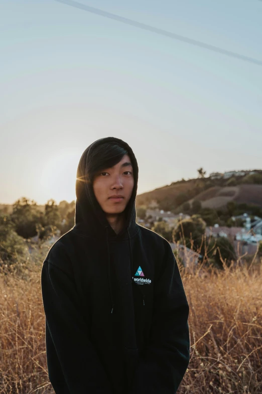 a man with a hoodie standing by the tall grass