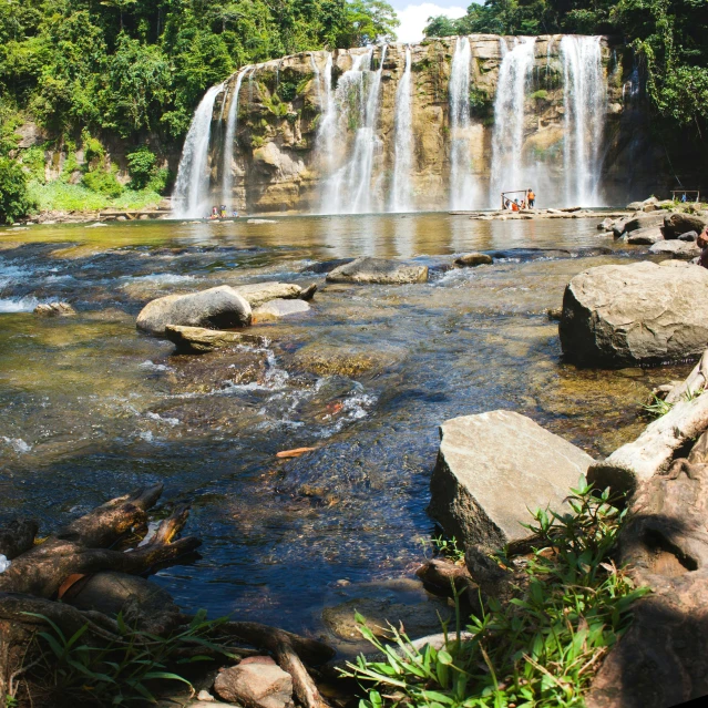 people are on a river by a large waterfall