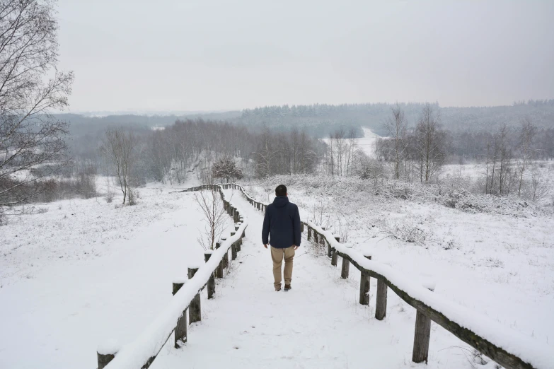 man walking up a snow covered pathway in winter