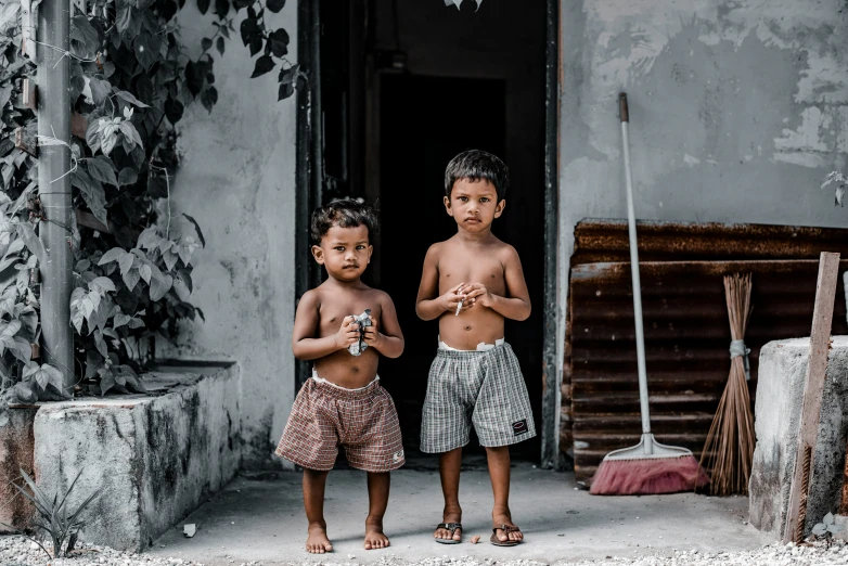 two young children standing in front of an old run down house