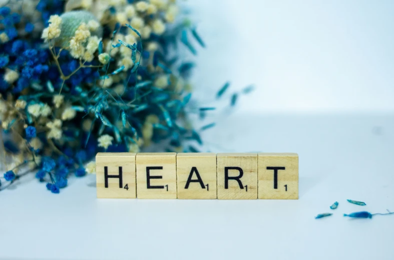 the word heart spelled on wooden blocks near a bouquet of flowers