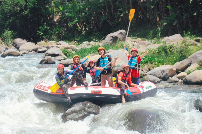 people with paddles and life jackets on inflatable raft riding through rapids