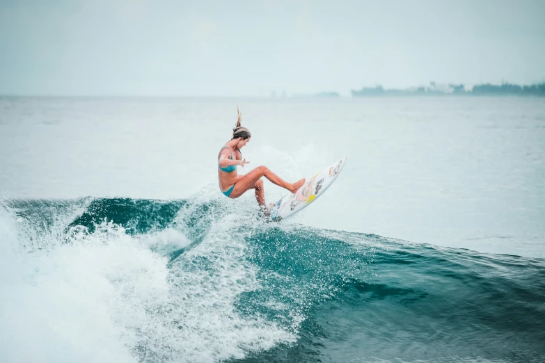 a woman riding on top of a wave on a surfboard