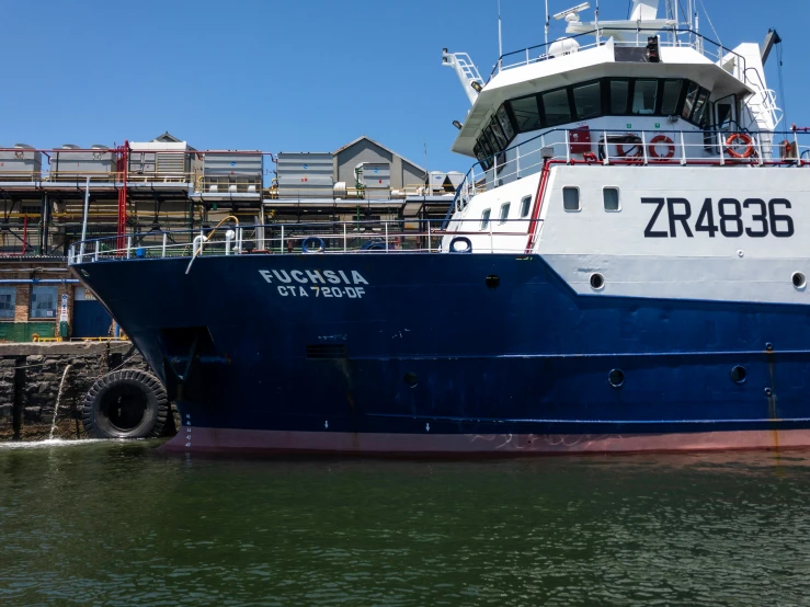 a boat sitting docked at the dock near some buildings