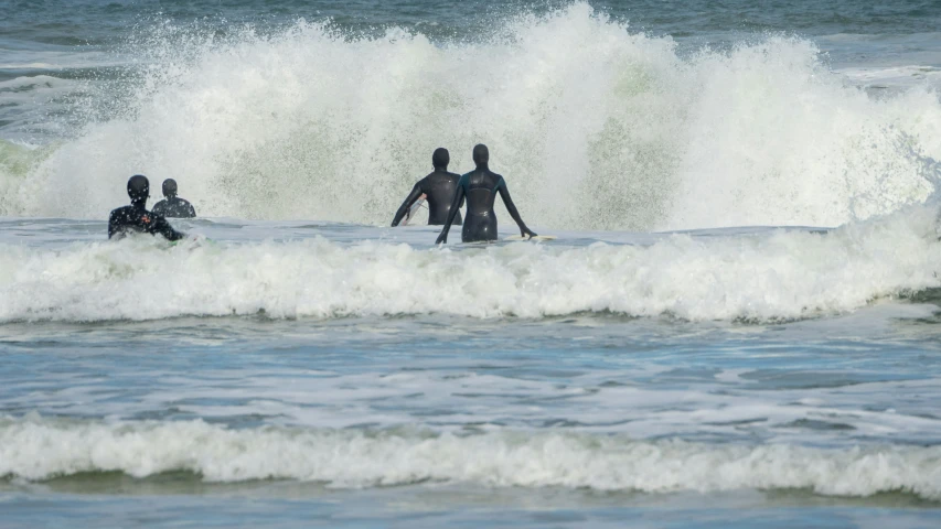 some surfers in black wet suits are riding the waves