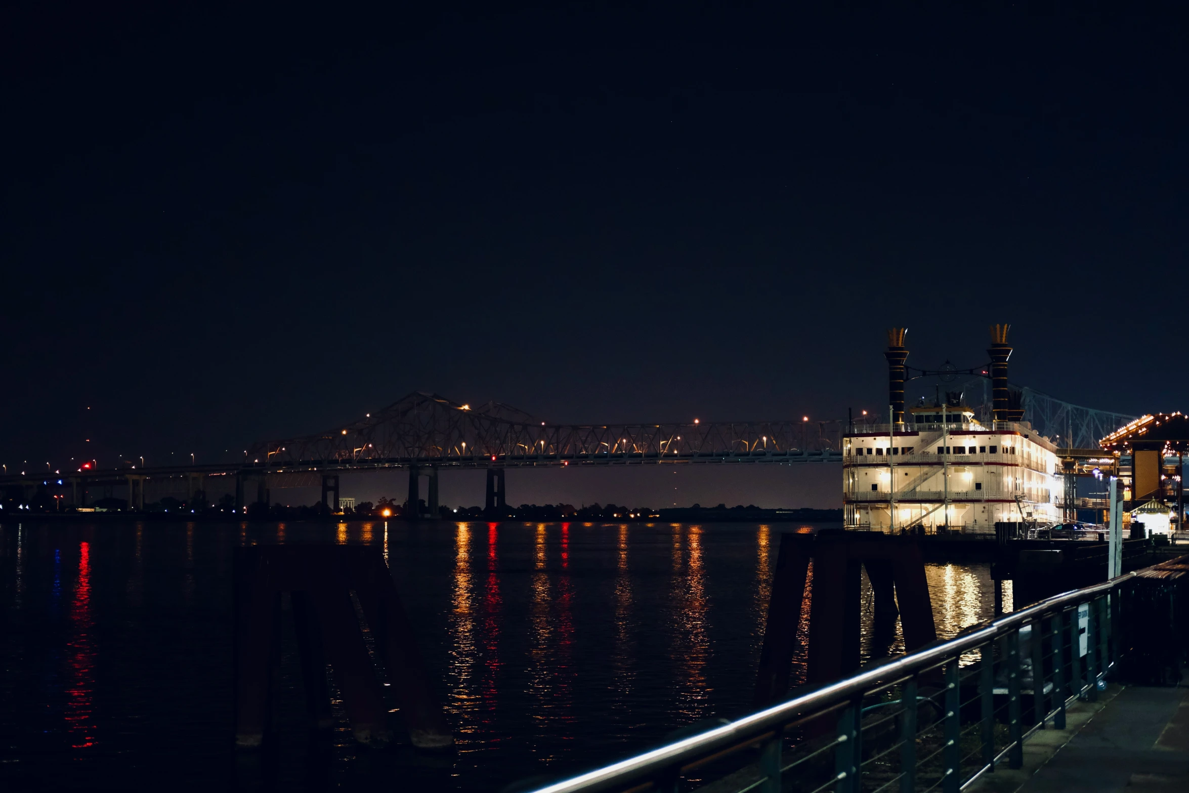 a ferry boat docked along the waterfront with lights reflecting on the water