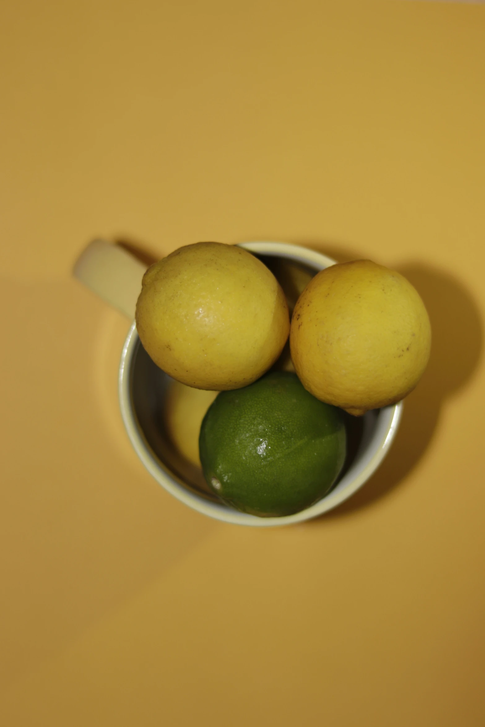 four lemons, one lime and a lime in a bowl