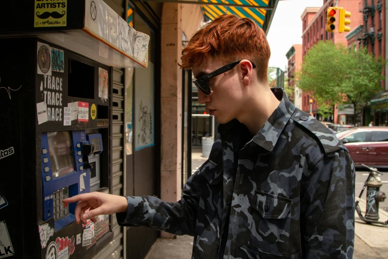 red haired man in camouflage looking at his newspaper