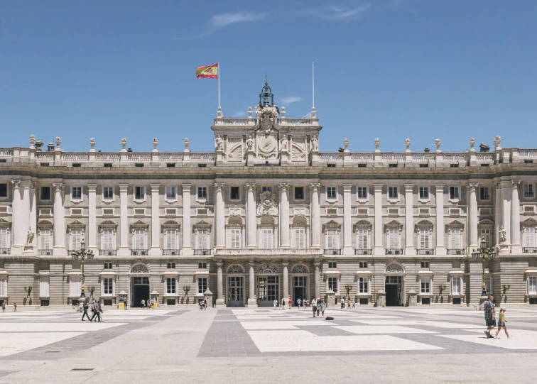 a building with people in front of it and flag on top