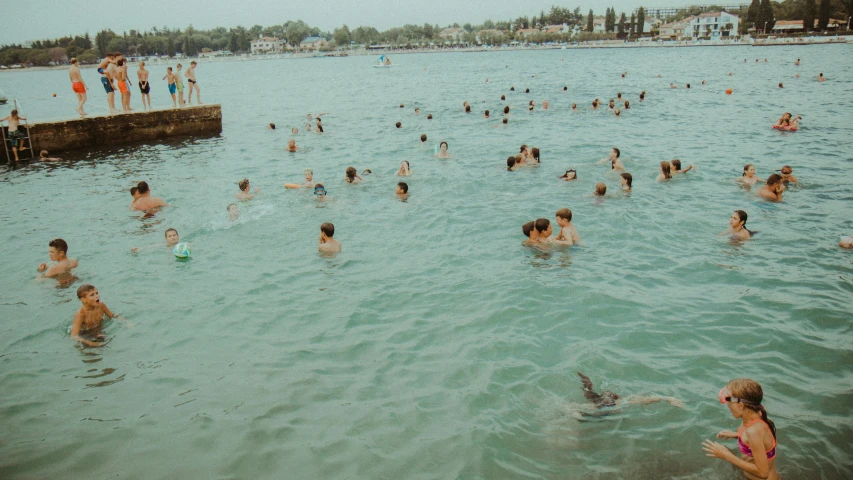 many people in water near a pier near the ocean