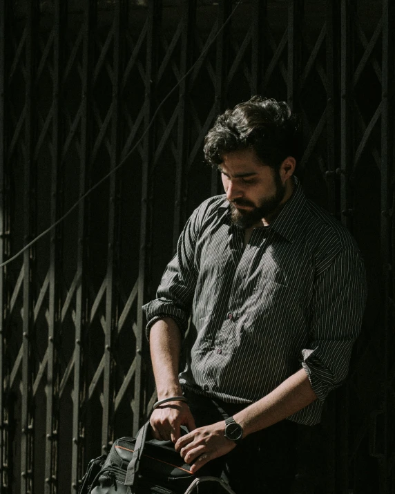 a man is walking near a gate holding his watch