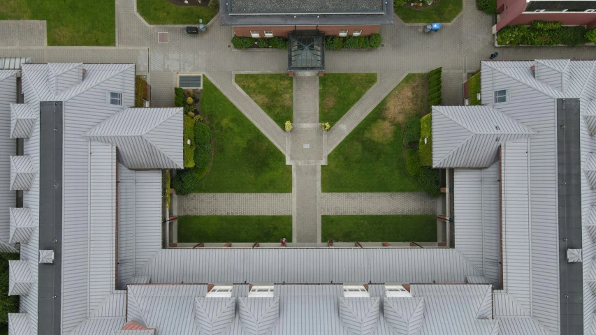 an aerial view of a courtyard with lawn and small building