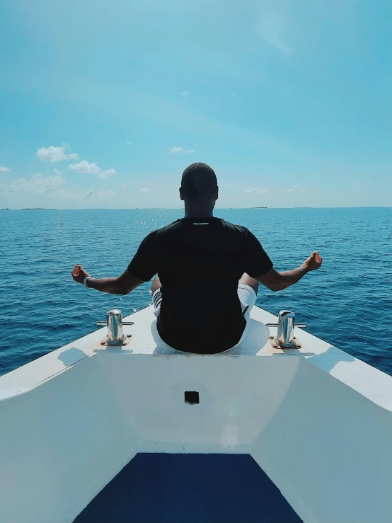 a man sits on the back of a boat in the ocean