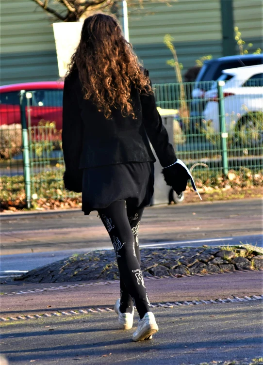 a woman walking down the sidewalk in black and white