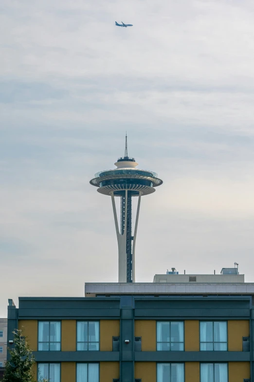 a tall airplane flying by a yellow building