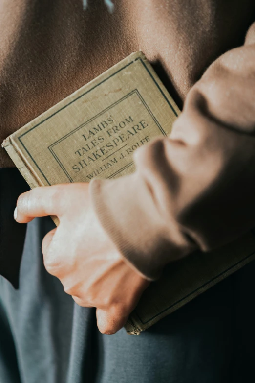 an old mans'hands are holding the book of james thomas shakespeare