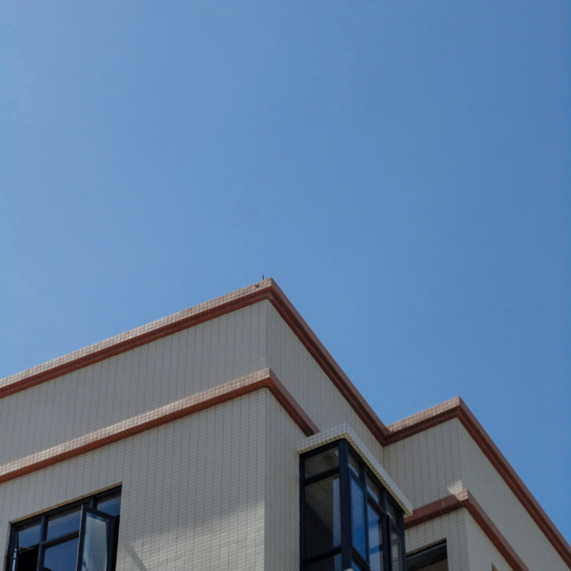 a large airplane flying high in the sky near a building