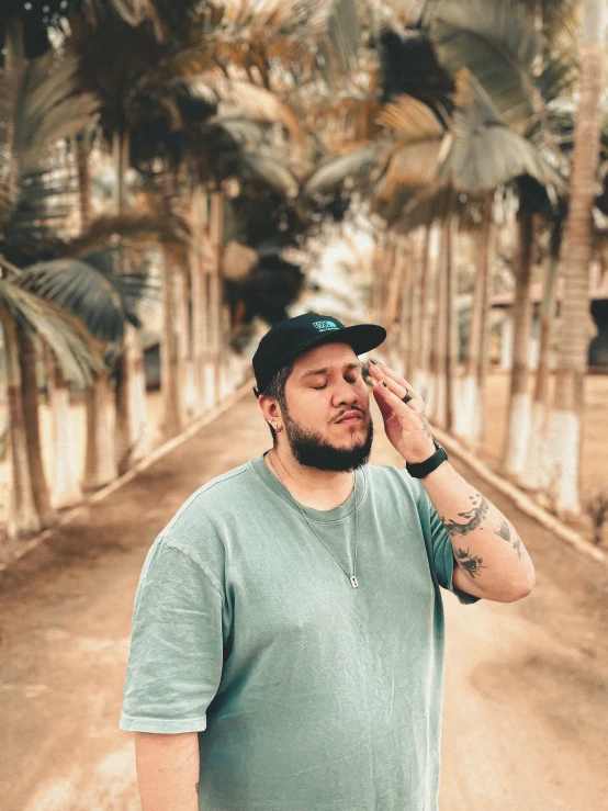 a man with a beard, green shirt and black hat on the phone