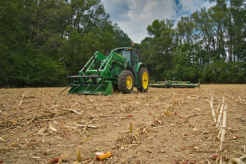 an agricultural tractor plowing a field of straw