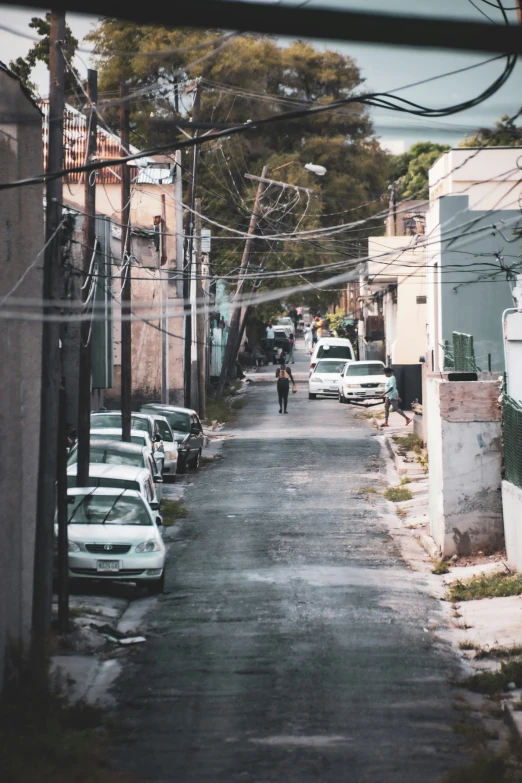 a narrow street with cars and pedestrians in the distance