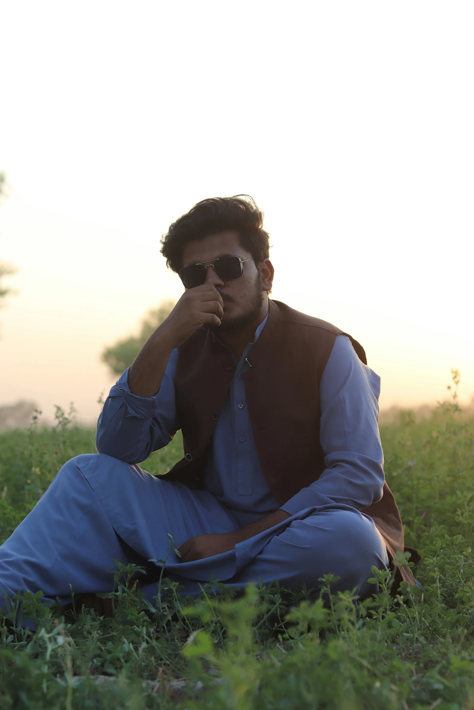 a man in sunglasses is sitting in a field