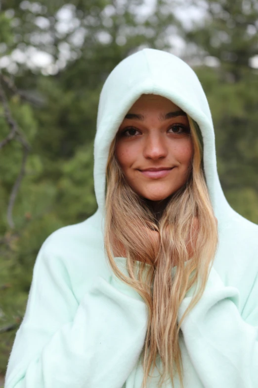 a beautiful blonde woman dressed in a blue hooded sweatshirt posing for a po