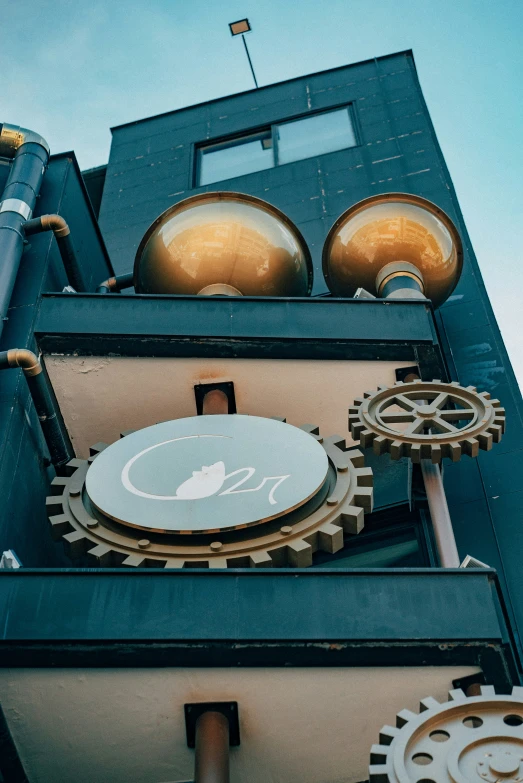 the top of an industrial building has gears and a clock