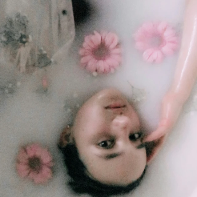 a girl laying in a bathtub with flowers on the walls