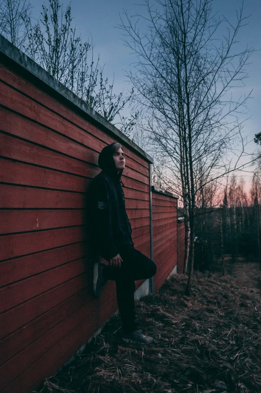 a person sitting against the side of a red building