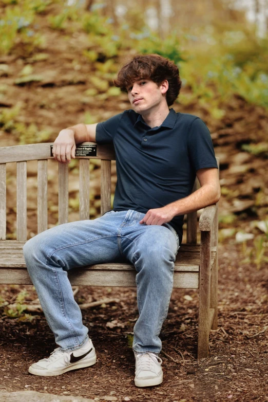 man with blue jeans sitting on a bench outside